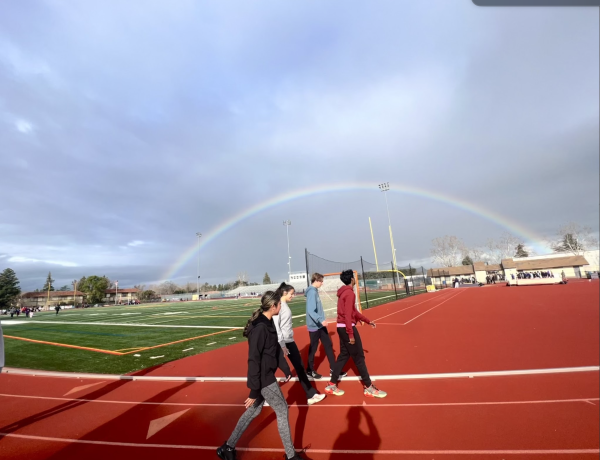 Track and field athletes take warmup laps during a cloudy spring day.